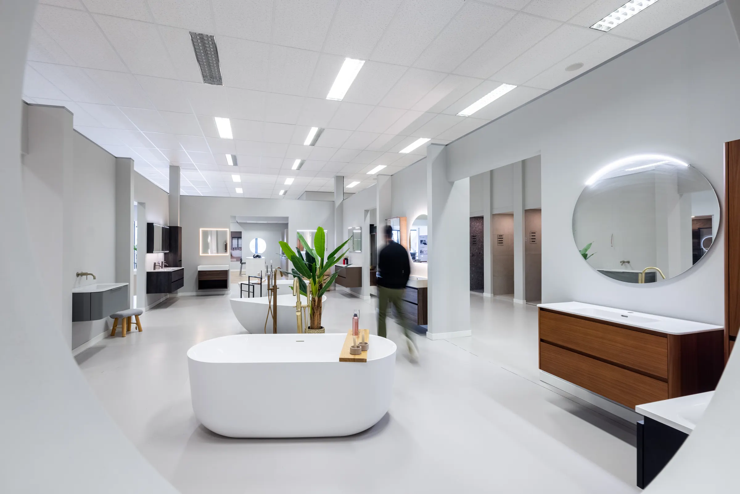 Lichte Sani4All-showroom met vrijstaand bad, ronde spiegel en badmeubels
