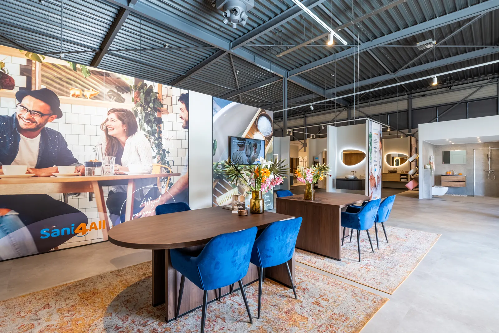 Showroom van Sani4All Harderwijk met adviestafel, blauwe stoelen en badkameropstellingen
